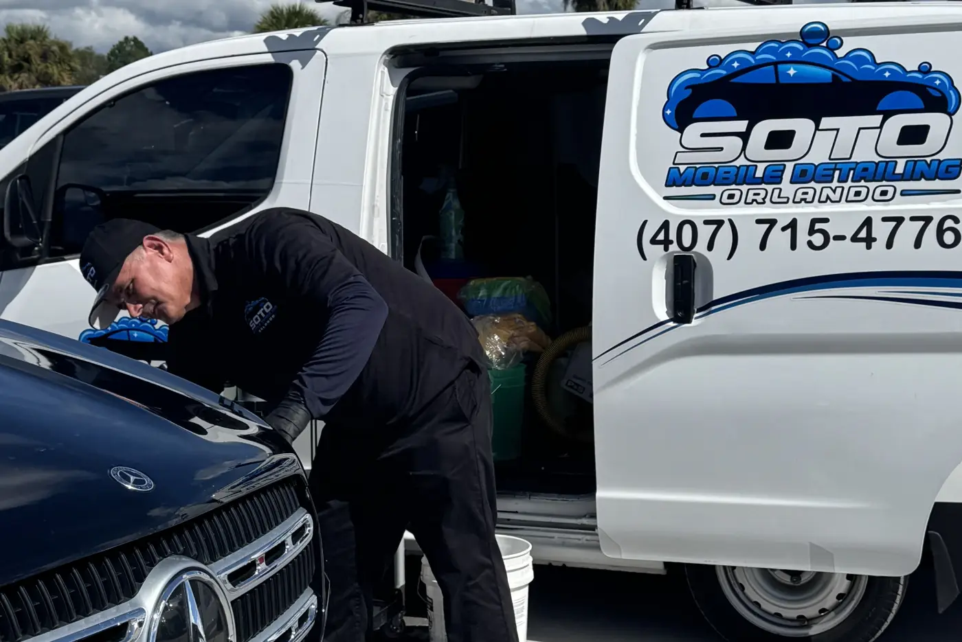 Soto detailer hand-washing the hood of a black car beside the branded Soto van