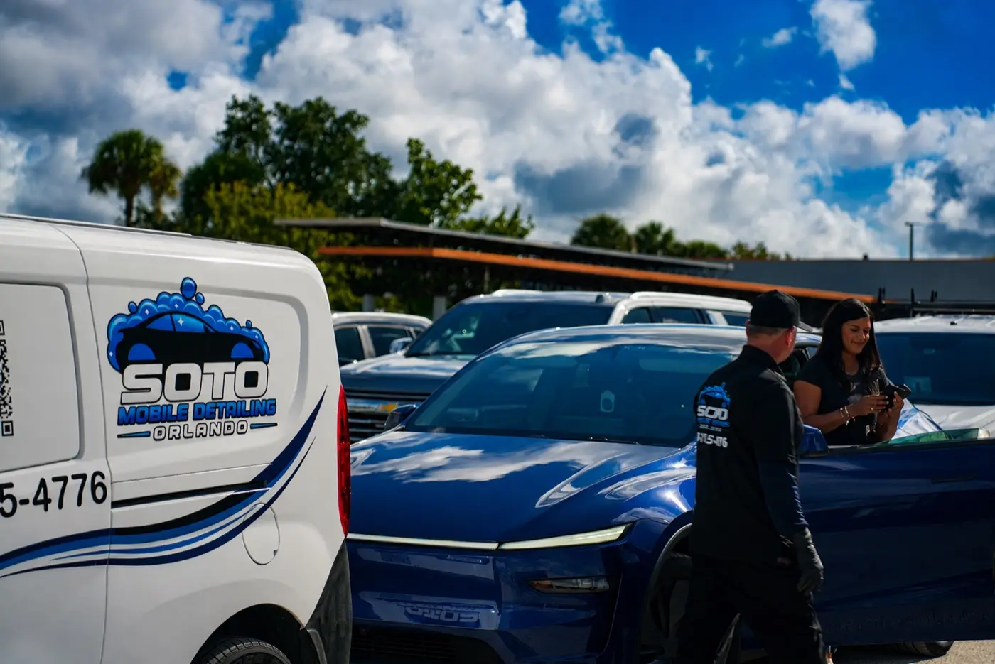 Customer and Soto detailer beside the freshly detailed blue car with the Soto van behind