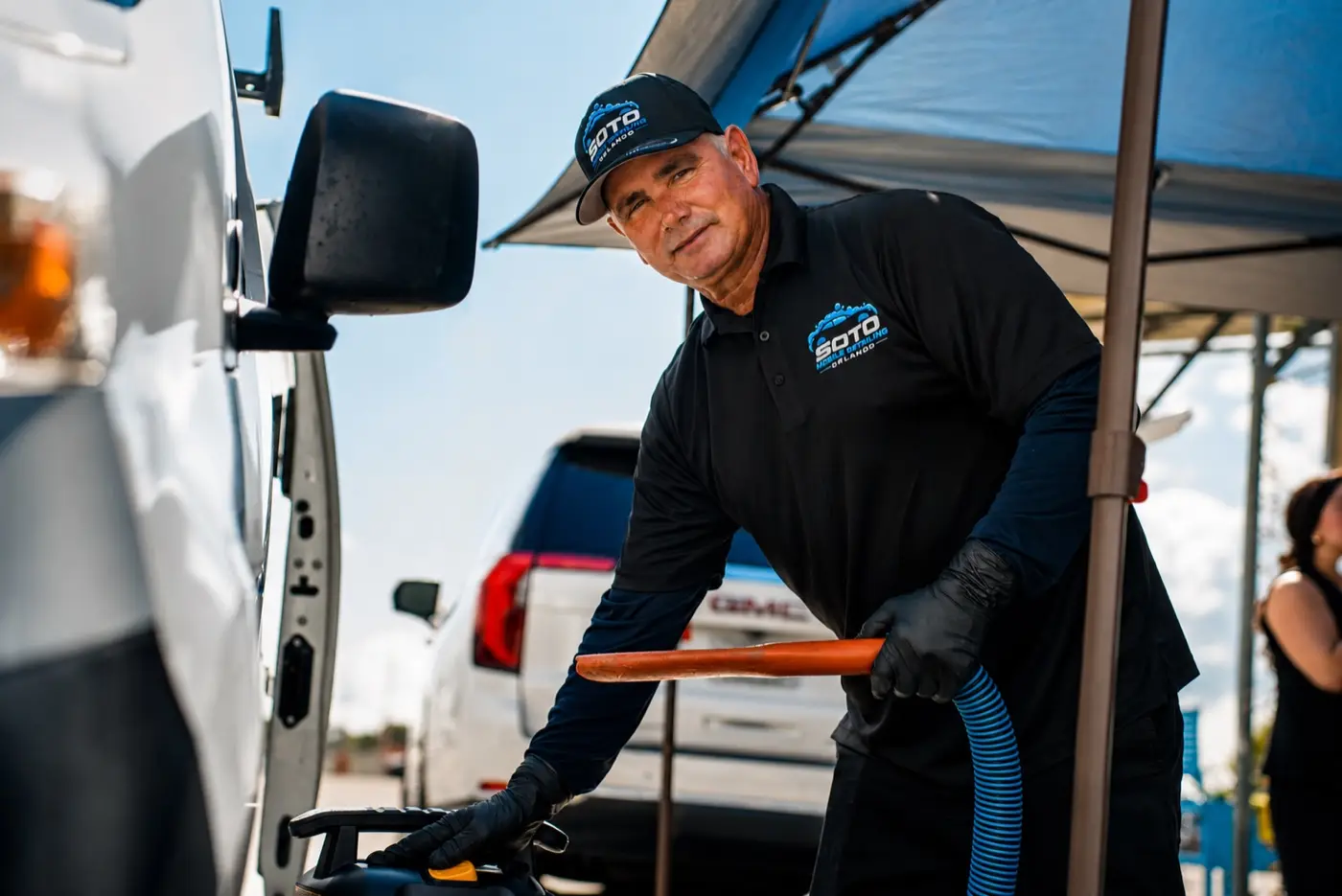 Soto detailer smiling while vacuuming a car under the mobile canopy