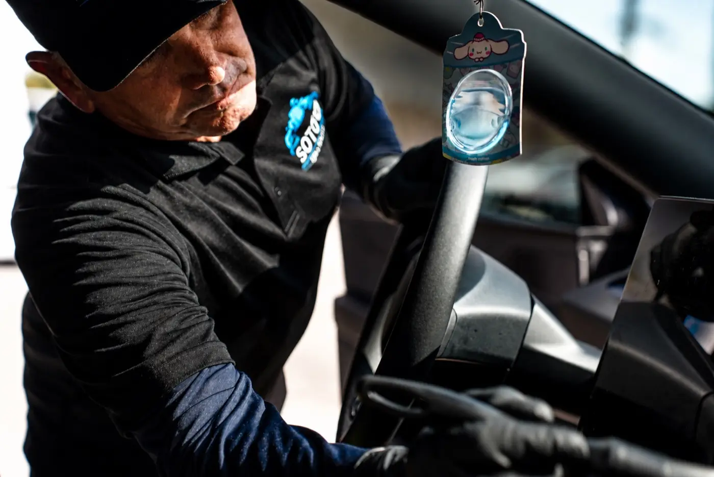 Soto detailer wiping the mirror area inside a customer car