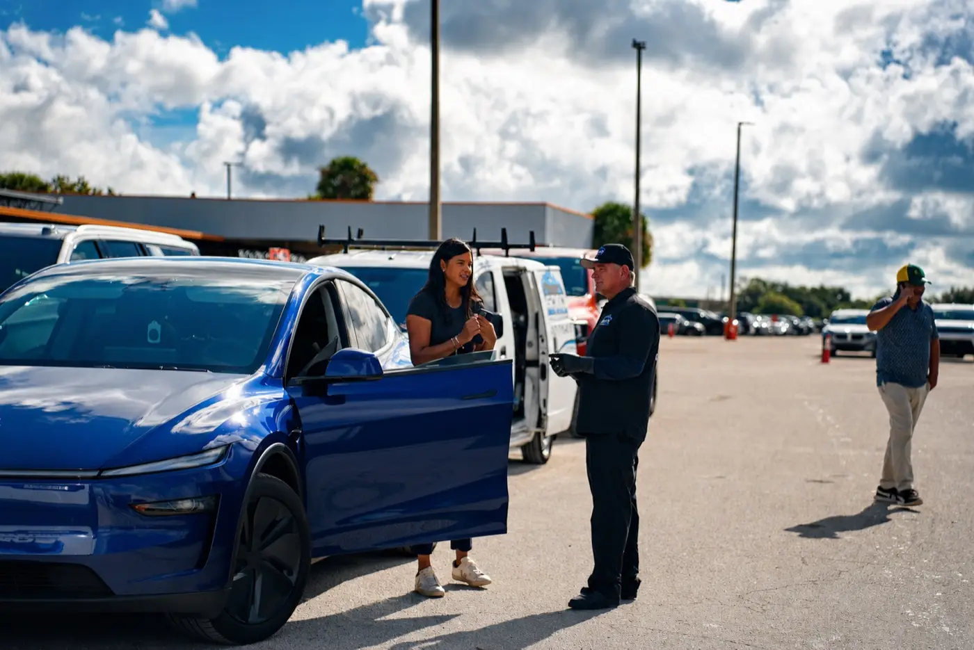 Soto van, blue car, customer and detailer on location in an Orlando lot