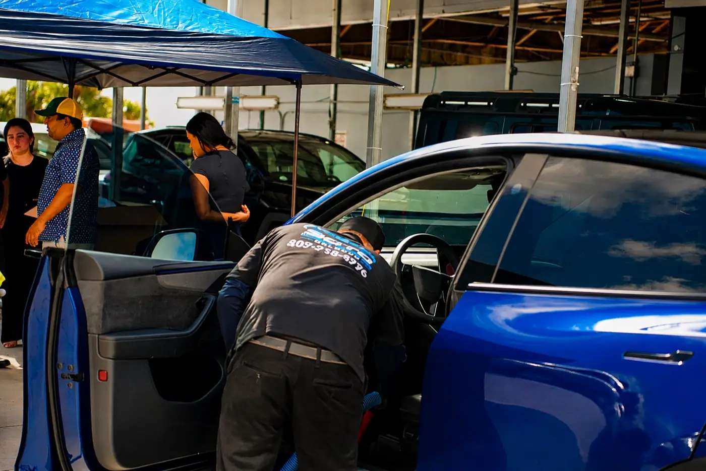 Mobile detailing company in Orlando, FL · detailer working the open door of a blue car under the mobile canopy